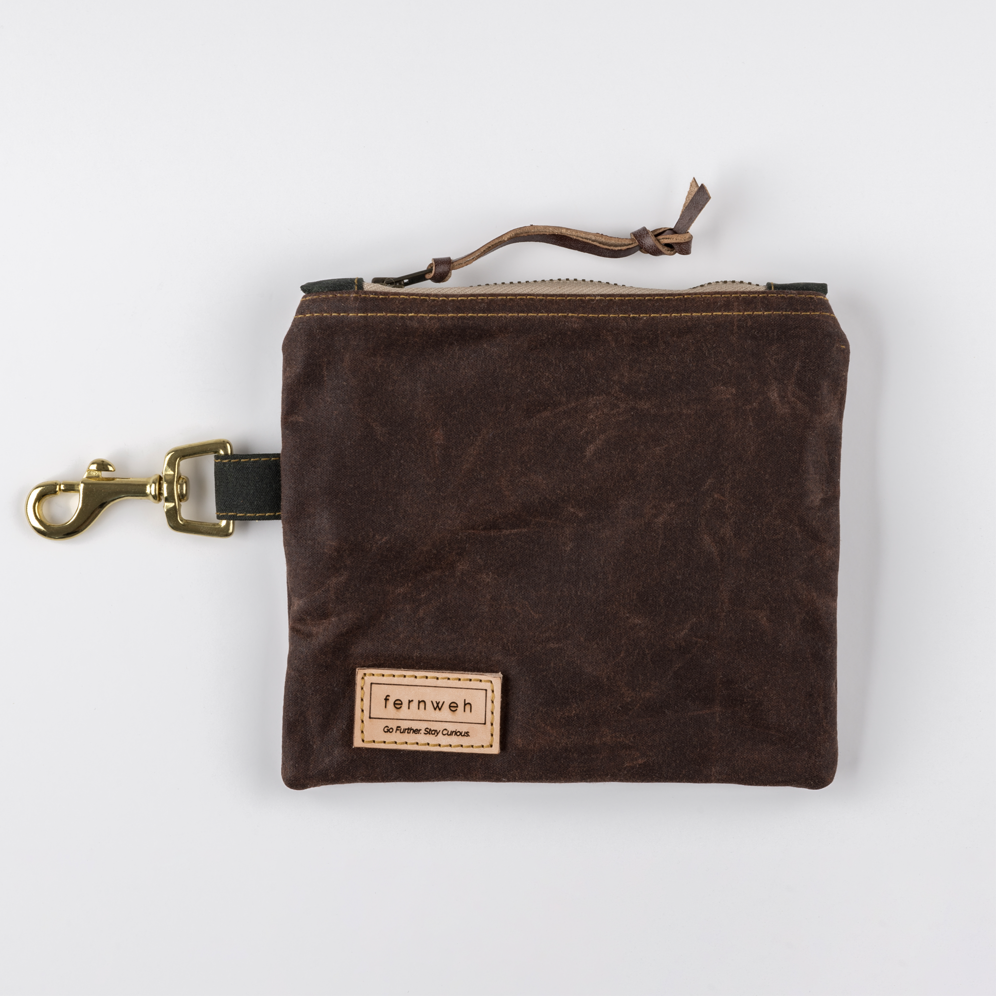Image shows a waxed cotton pouch on a plain background. The pouch has a beige zip and a solid brass key clip on the left hand side.  Photography by Jo Hounsome photography.